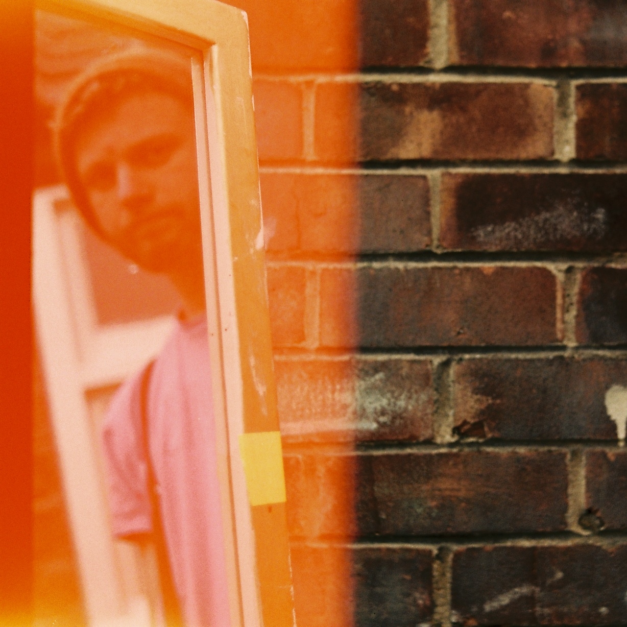 James Mcilwrath (young white man in beanie and pink t-shirt) reflected in a window