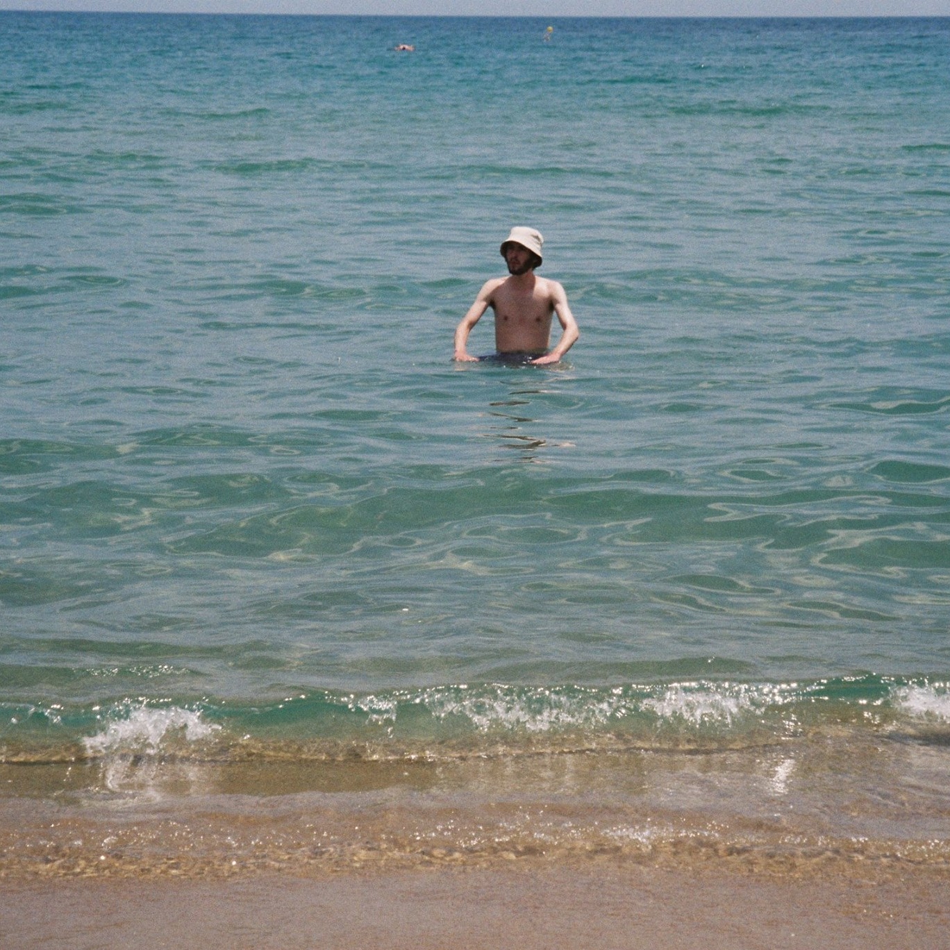 Max (young white man in a hat) pictured at a distance swimming in the sea