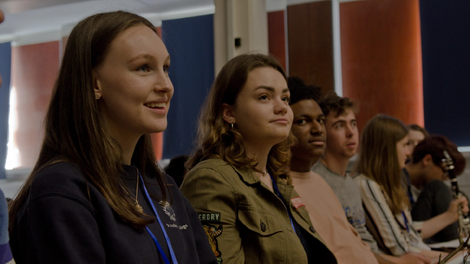Young people sit in a row facing forwards and smiling